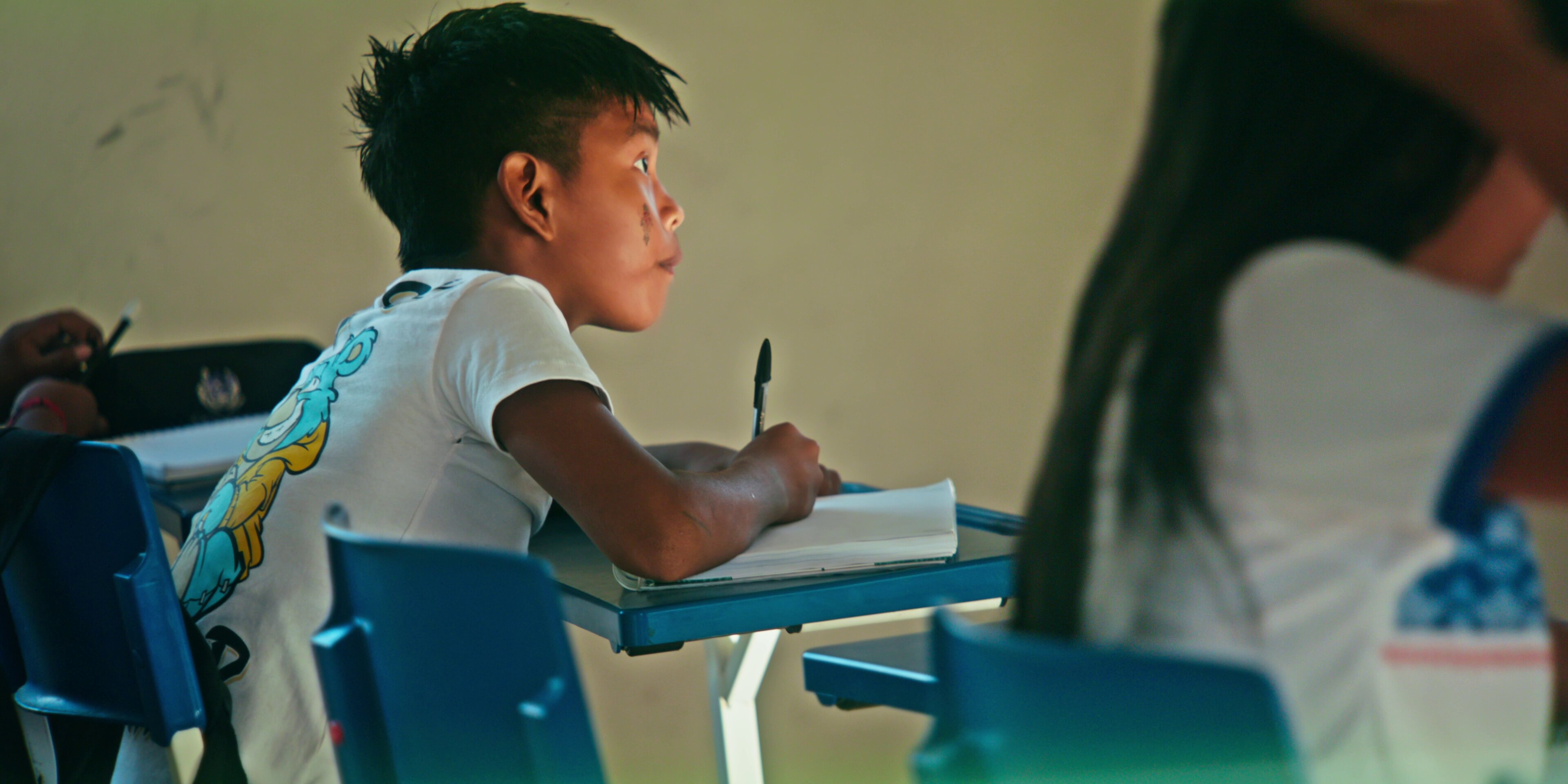 Criança escrevendo no caderno na escola